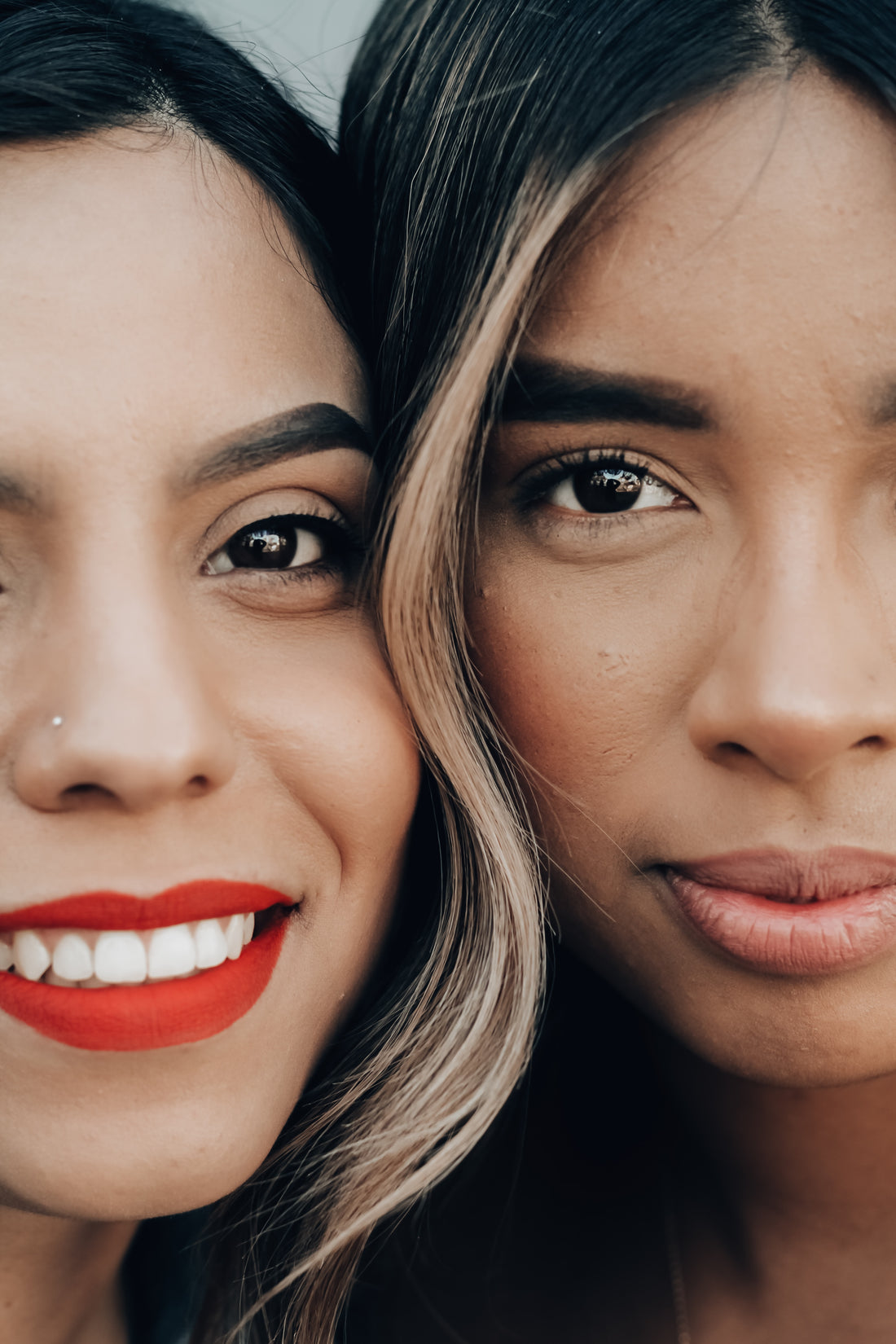 two girls, one light tone and one brown ton, stare into the camera confidently